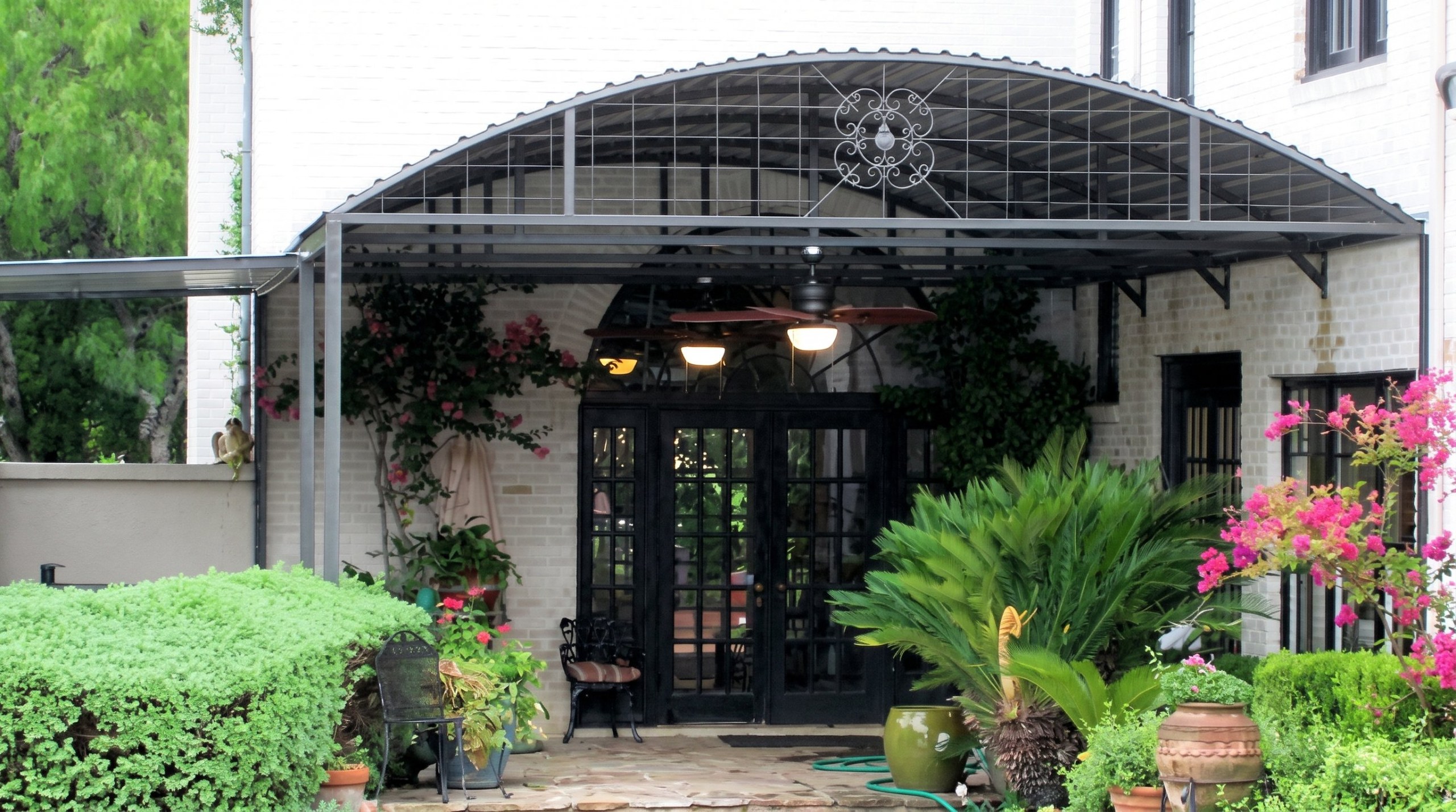 Curved steel patio awning with decorative ironwork in Alamo Heights, Texas