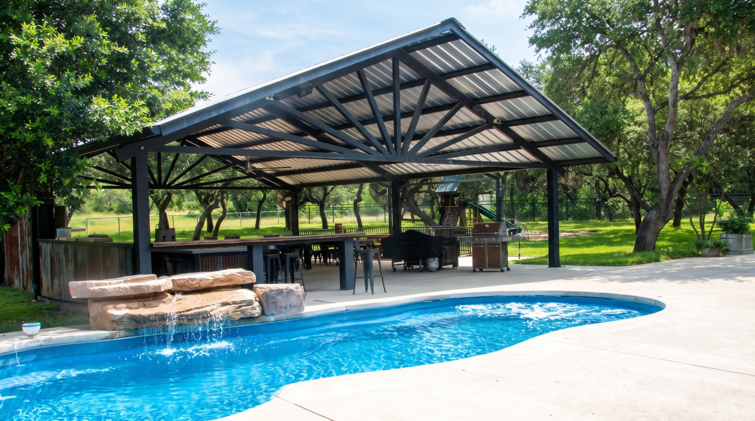 Large steel pavilion with outdoor kitchen next to a pool in Helotes, Texas